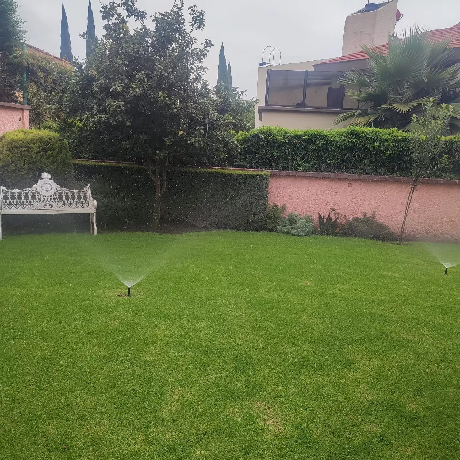 Jardín residencial con aspersores emergentes regando el pasto